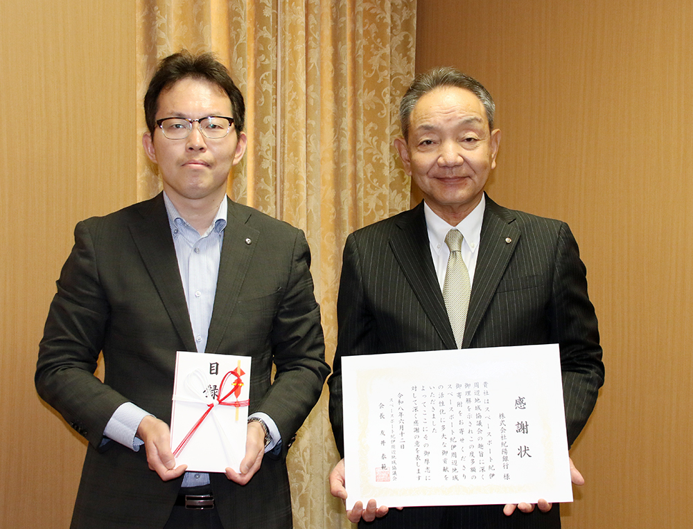 寄付目録、感謝状を手にする友井副知事㊧、原口頭取