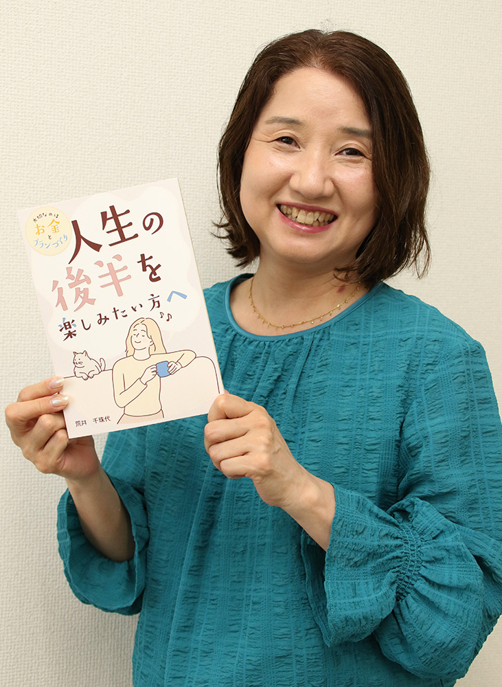 著書を手に笑顔の荒井さん