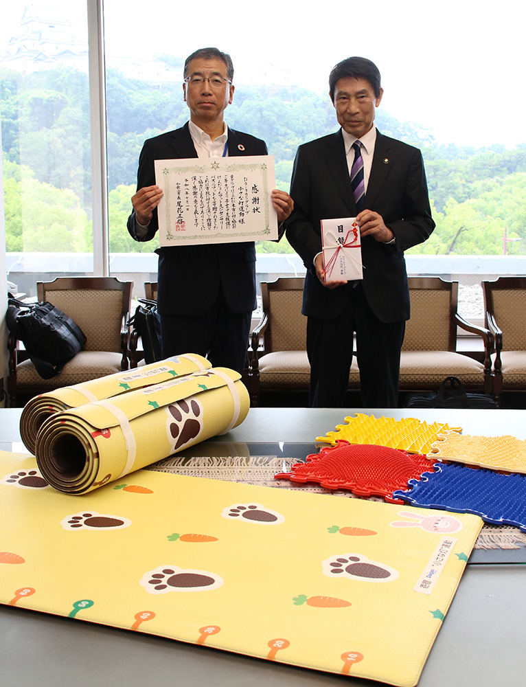 寄贈品を前に堀内統括支配人㊧と尾花市長