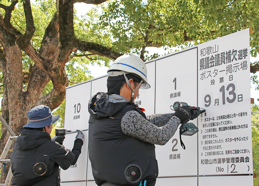 ポスター掲示板を設置する作業員ら
