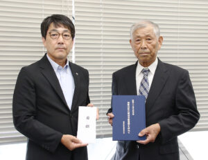 寄贈した記念誌と目録を手に田中会長㊨と今西教育長
