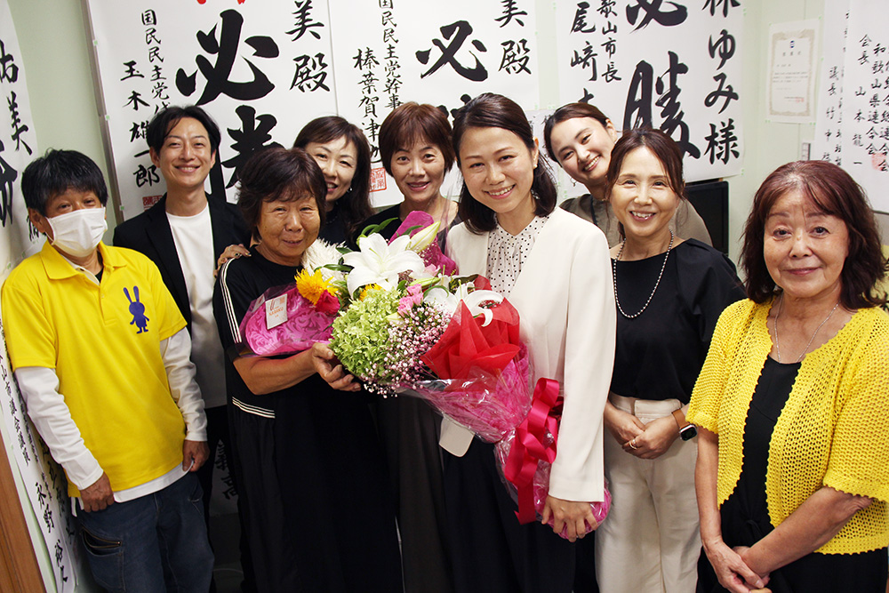 花束を手に支援者と喜びを分かち合う林さん(中央)