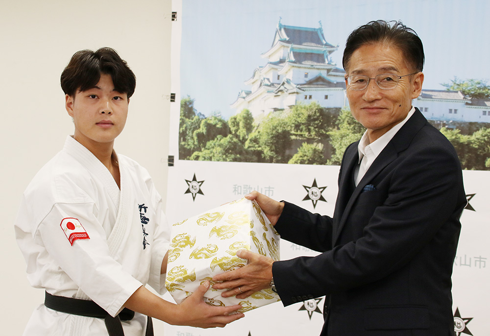 選手を代表して尾﨑市長㊨から記念品を受け取る角野さん