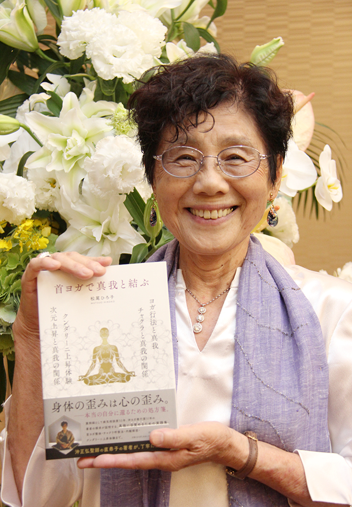 新書を手に笑顔の松尾さん