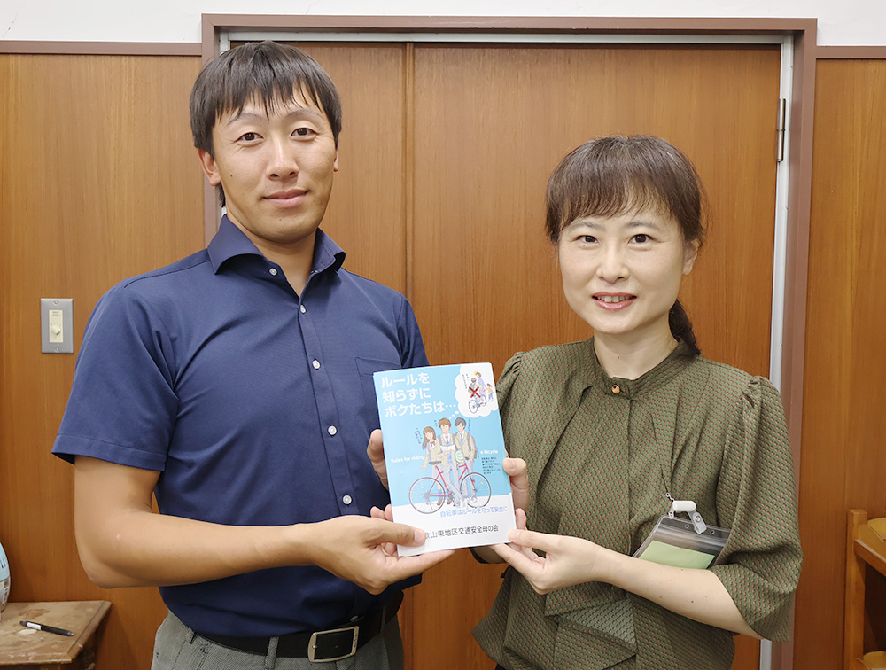 尾﨑会長㊨が日野教諭に手渡した