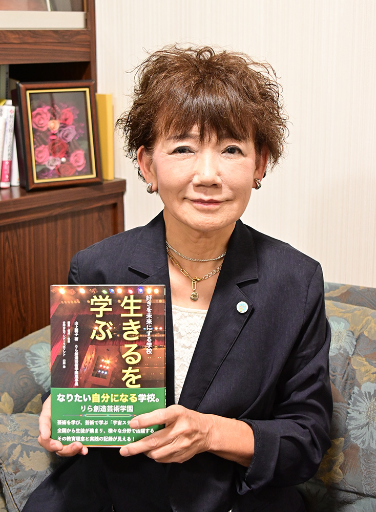書籍『生きるを学ぶ』を手に山上理事長