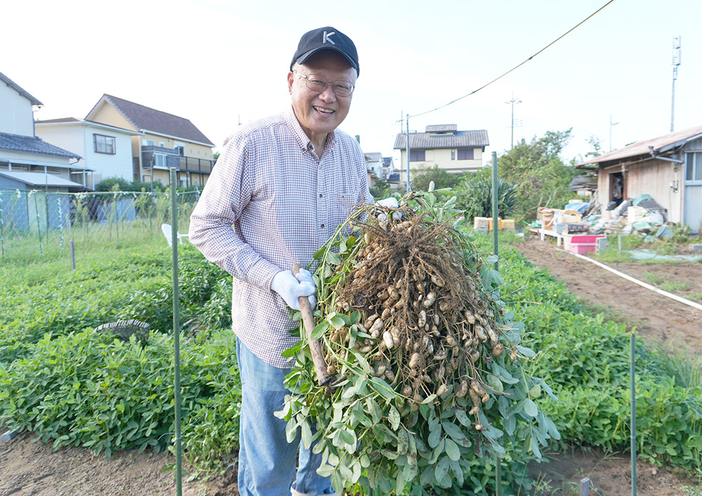 収穫した落花生を手に笑顔の松本さん